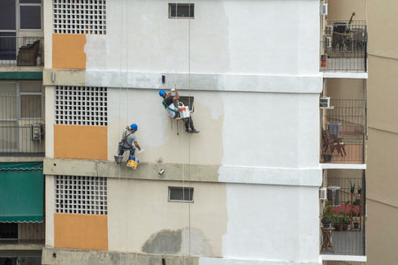Rio, Brazil - november 04, 2022 - painter works on residential building facade recovery by rope as a climberのeditorial素材