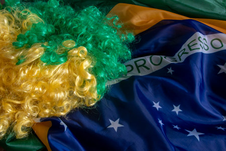 flag of Brazil in a wave filling the frame and a green and yellow wigの写真素材