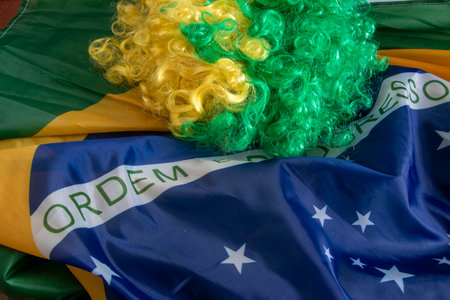 flag of Brazil in a wave filling the frame and a green and yellow wigの写真素材