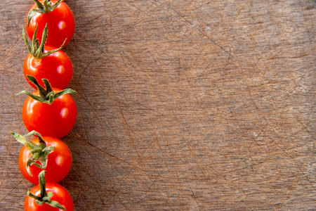 Cherry tomato forming side frame on scratched wooden background for writing textの写真素材