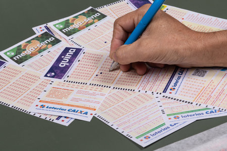 Rio, Brazil - July 20, 2022: person filling out Caixa Economica Federal lottery card, the only official betting method in Brazilのeditorial素材