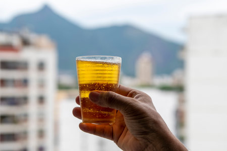 male hand holding a glass of beer on the background of the cityの写真素材