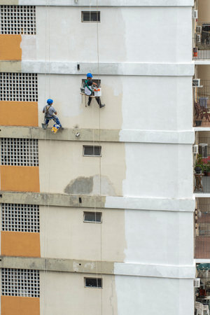 Rio, Brazil - november 04, 2022 - painter works on residential building facade recovery by rope as a climberのeditorial素材