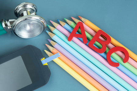 Back to school concept for kids with diabetes represented by colored pencils and glucometerの写真素材