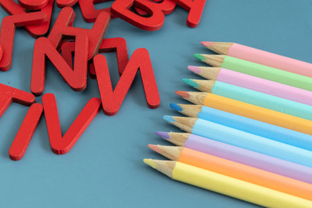 Back to school concept with assorted letters and colored pencils in pastel colors on blue backgroundの写真素材