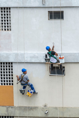 Rio, Brazil - november 04, 2022 - painter works on residential building facade recovery by rope as a climberのeditorial素材