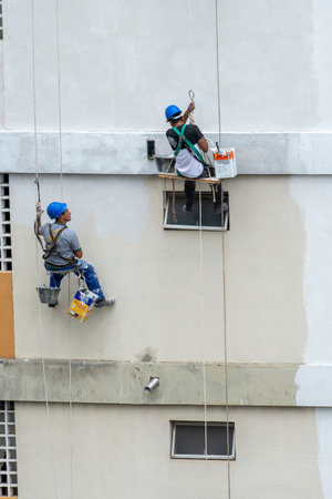 Rio, Brazil - november 04, 2022 - painter works on residential building facade recovery by rope as a climberのeditorial素材