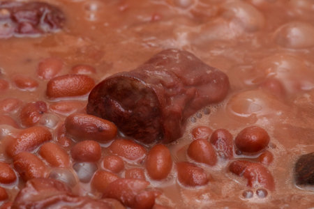 Brown brazilian beans being cooked showing details of the grains and sausages to tasteの写真素材