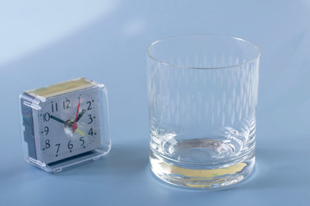 Detail of the person filling the glass with water. Concept of reminding hydration time on blue backgroundの写真素材