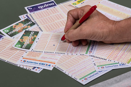 Rio, Brazil - July 20, 2022: person filling out Caixa Economica Federal lottery card, the only official betting method in Brazilのeditorial素材