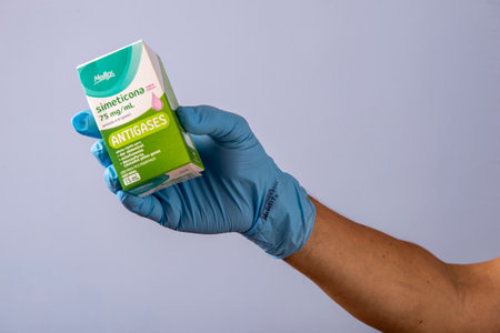 Rio, Brazil - January 27, 2023, hand with protective rubber glove holding medicine box, simethiconeのeditorial素材