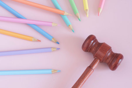 Pastel colored pencils with a justice gavel, top view on pink background, back to school concept