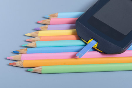 Back to school concept for kids with diabetes represented by colored pencils and glucometerの写真素材