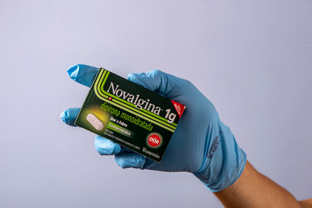 Rio, Brazil - January 27, 2023, doctor hand with protective rubber glove holding medicine box, dipyrone monohydrateのeditorial素材