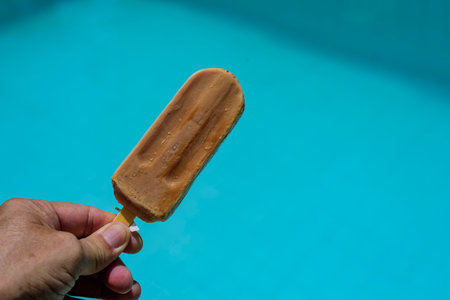 hand holding ice cream on blue background representing summerの写真素材