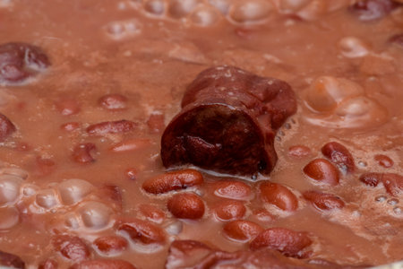Brown brazilian beans being cooked showing details of the grains and sausages to tasteの写真素材