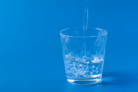 Unfilled glass of water on blue backgroundの写真素材