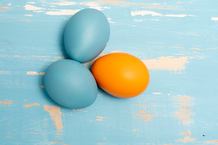 Eggs symbolizing the Easter holiday in blue and orange color on a background of aged wood in the same colorの写真素材