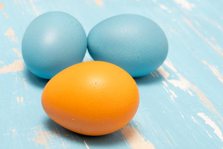 Eggs symbolizing the Easter holiday in blue and orange color on a background of aged wood in the same colorの写真素材