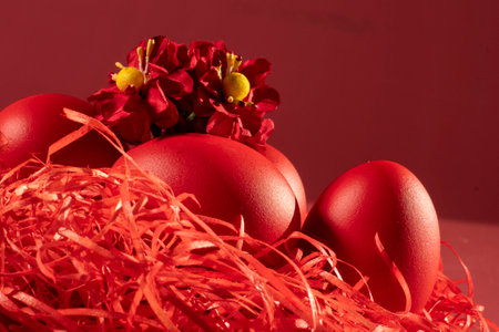 Red easter eggs in a nest with flowers on a red backgroundの写真素材