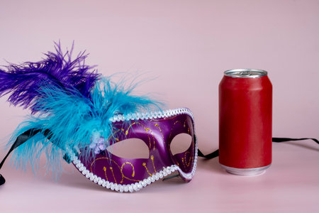 Carnival mask, can of champagne and feathers on pink backgroundの写真素材