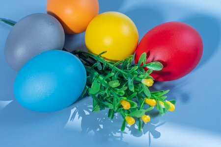 Colorful Easter eggs on a blue background with green grass and flowersの写真素材