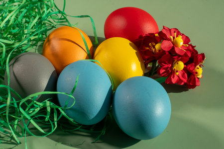 Colorful easter eggs in nest with flowers on green background.の写真素材