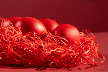 Colored eggs symbolize Easter in shades of red on strawの写真素材
