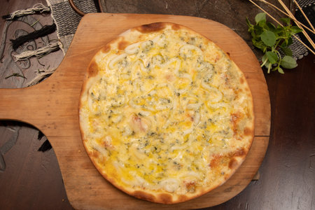 Pizza with cheese and herbs on a wooden board, top viewの写真素材