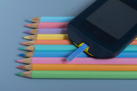 Back to school concept for kids with diabetes represented by colored pencils and glucometerの写真素材