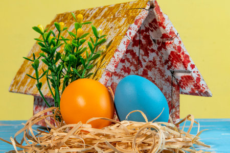 colorful eggs symbolizing easter with a toy house and flowers like a gardenの写真素材