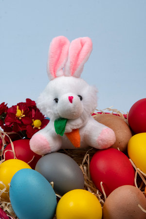 Easter bunny and colorful eggs in a nest of straw on a blue backgroundの写真素材