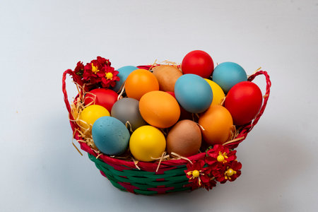 basket with straw and eggs decorated for the celebration of Christian Easter in light backgroundの写真素材