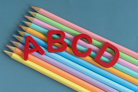 Back to school concept with assorted letters and colored pencils in pastel colors on blue backgroundの写真素材