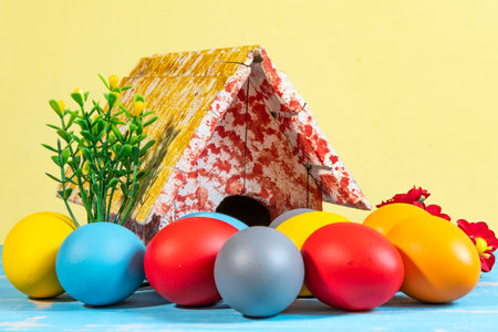 colorful eggs symbolizing easter with a toy house and flowers like a gardenの写真素材