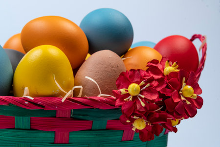 basket with straw and eggs decorated for the celebration of Christian Easter in light backgroundの写真素材