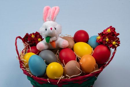 basket with straw, bunny and eggs decorated for the celebration of Christian Easter in light backgroundの写真素材