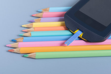 Back to school concept for kids with diabetes represented by colored pencils and glucometerの写真素材