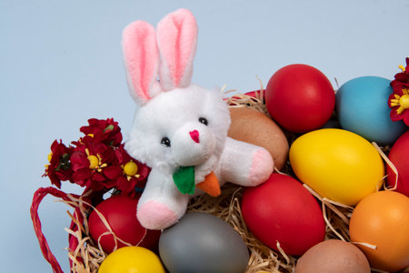 basket with straw, bunny and eggs decorated for the celebration of Christian Easter in light backgroundの写真素材