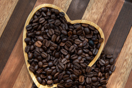 coffee beans in heart-shaped tray and falling out, representing love of coffeeの写真素材