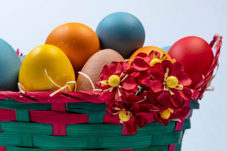 basket with straw and eggs decorated for the celebration of Christian Easter in light backgroundの写真素材