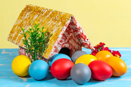 colorful eggs symbolizing easter with a toy house and flowers like a gardenの写真素材