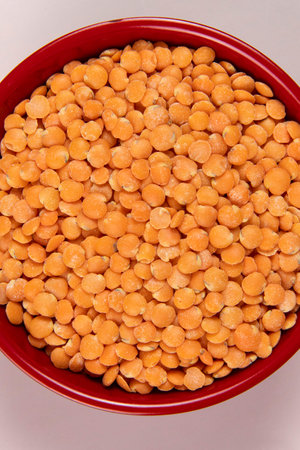 Red lentil in plastic bowl isolated on pink background. top viewの写真素材