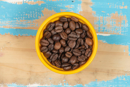 bowl with roasted coffee beans on blue rustic wooden table, top viewの写真素材