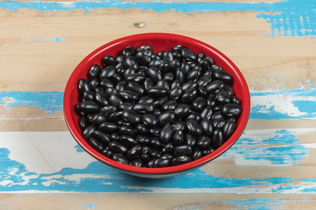 bowl with black bean beans on blue rustic wooden table, up viewの写真素材