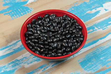 bowl with black bean beans on blue rustic wooden table, up viewの写真素材