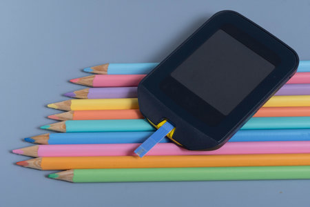 Back to school concept for kids with diabetes represented by colored pencils and glucometerの写真素材