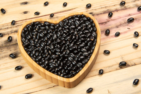 heart shaped black bean bowl on wooden table, top viewの写真素材