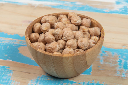 chickpeas in a wooden bowl on a blue wooden backgroundの写真素材