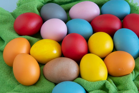eggs painted in different colors to celebrate Easter on a green cloth backgroundの写真素材